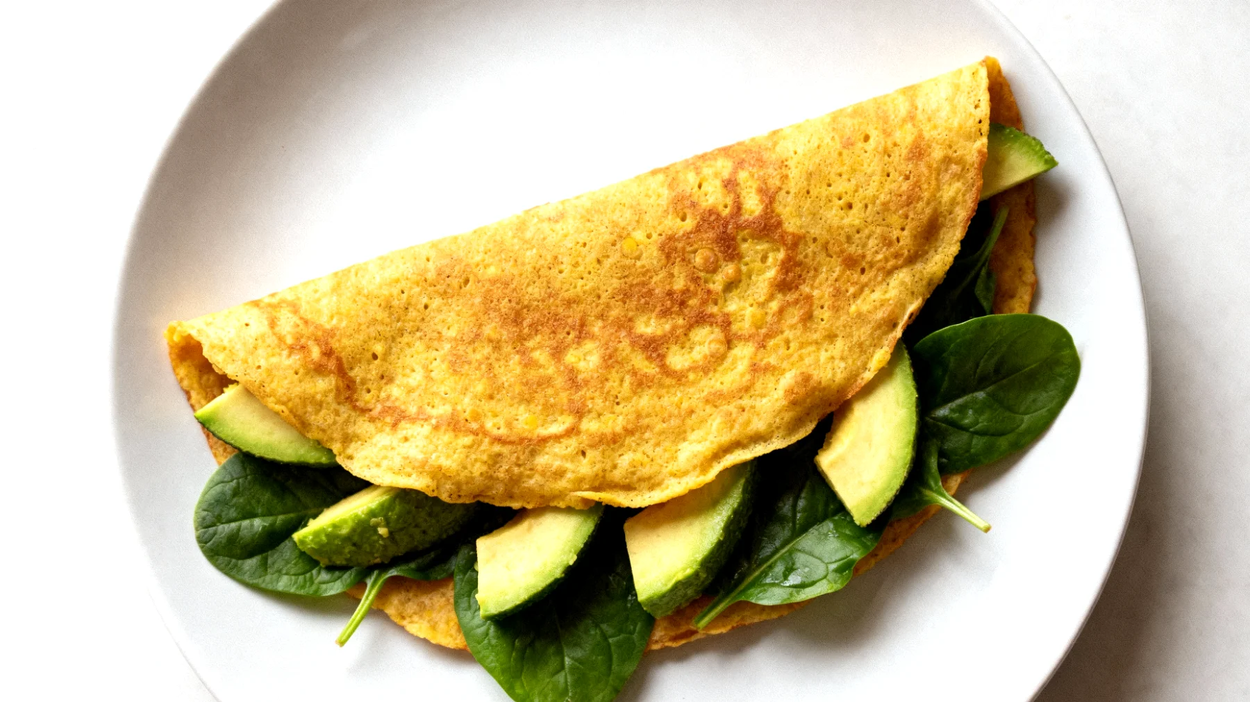 Kichererbsen-Pancakes mit Avocado und Spinat (Socca-Wraps)"